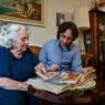 photo of an older woman and younger man looking at a photo album