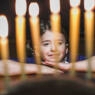 photo of a girl looking at hanukkah candles